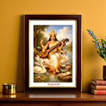 Framed artwork of a Maa Saraswati playing a stringed instrument on a saffron wall.